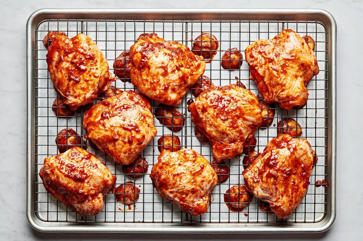 chicken tossed with harissa, olive oil, salt, garlic powder, and onion powder on a cooling rack on top of a baking sheet