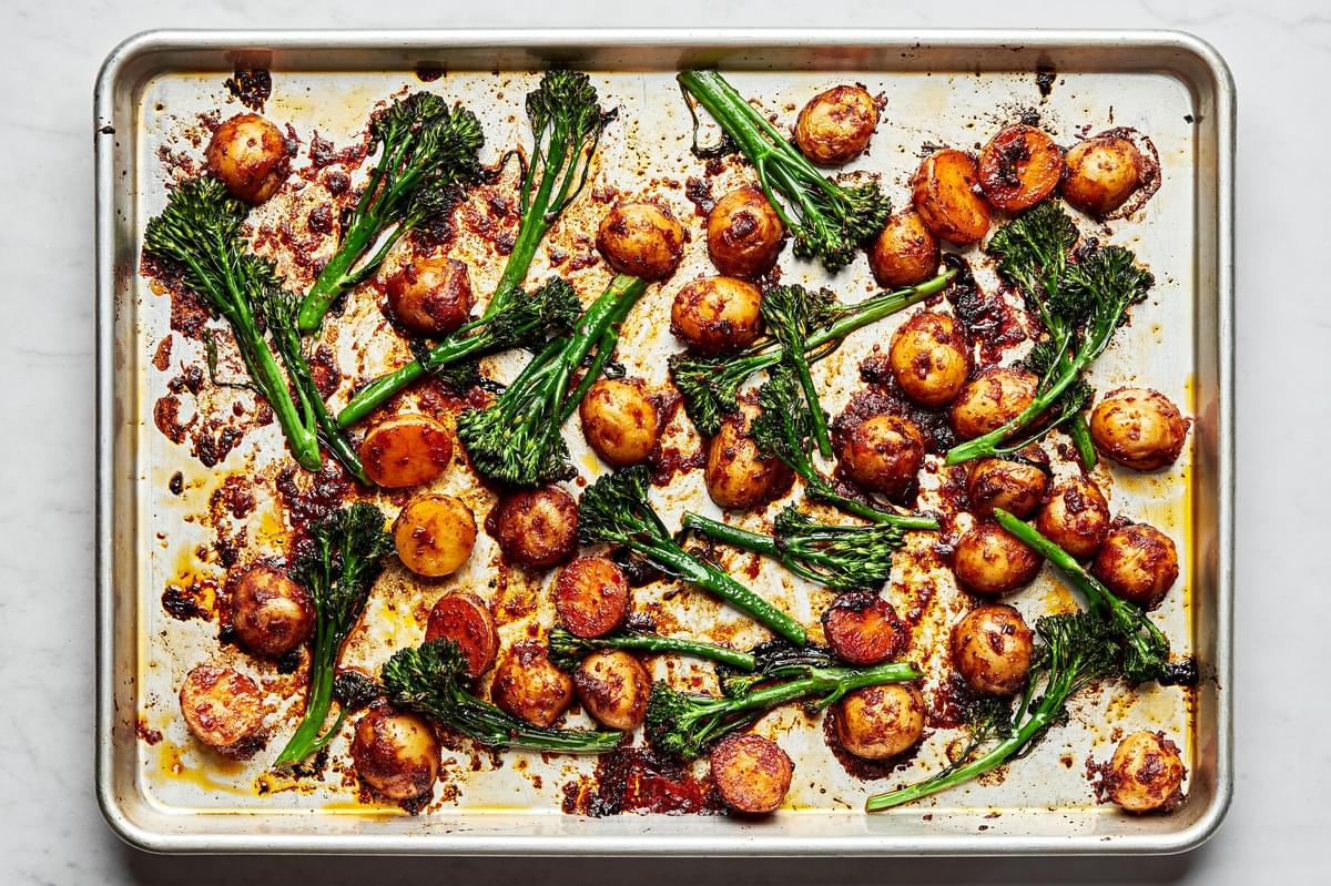 roasted potatoes and broccoli in a harissa sauce on a baking sheet