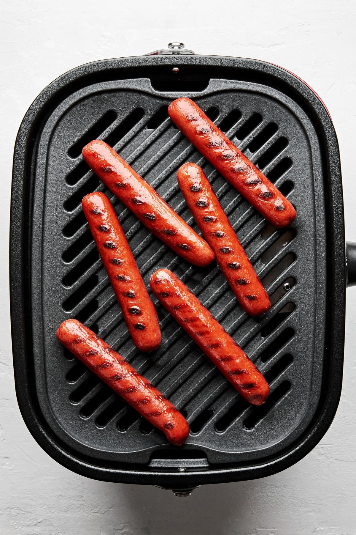 hot dogs cooking on a griddle