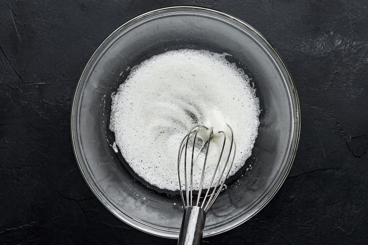 egg whites being whisked in a bowl until frothy