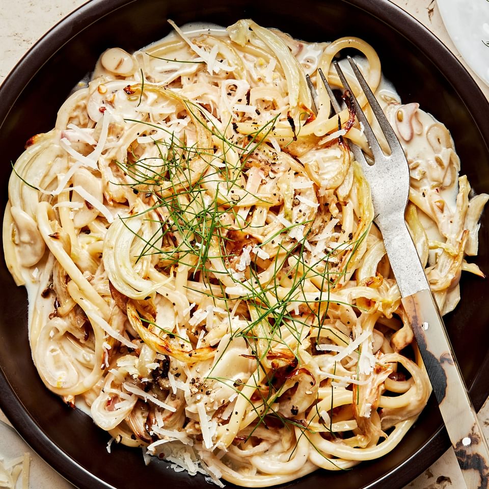 a bowl of pasta with roasted fennel made with garlic, white wine, heavy cream lemon juice & zest. topped with parmesan