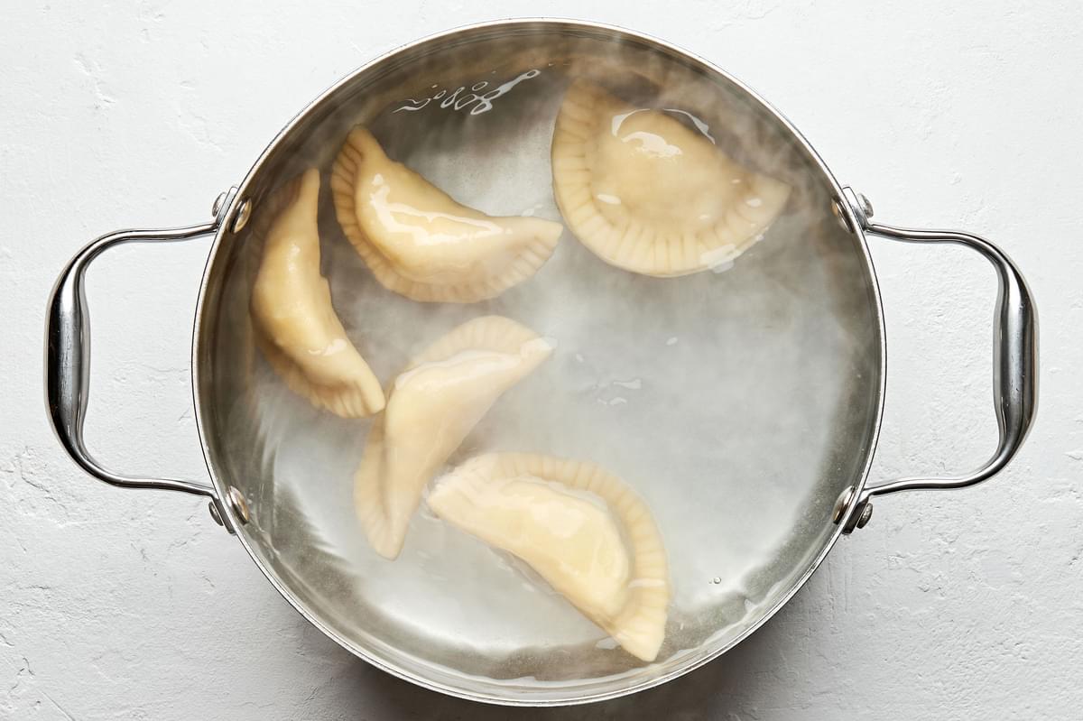 pierogis being boiled in a large pot of water