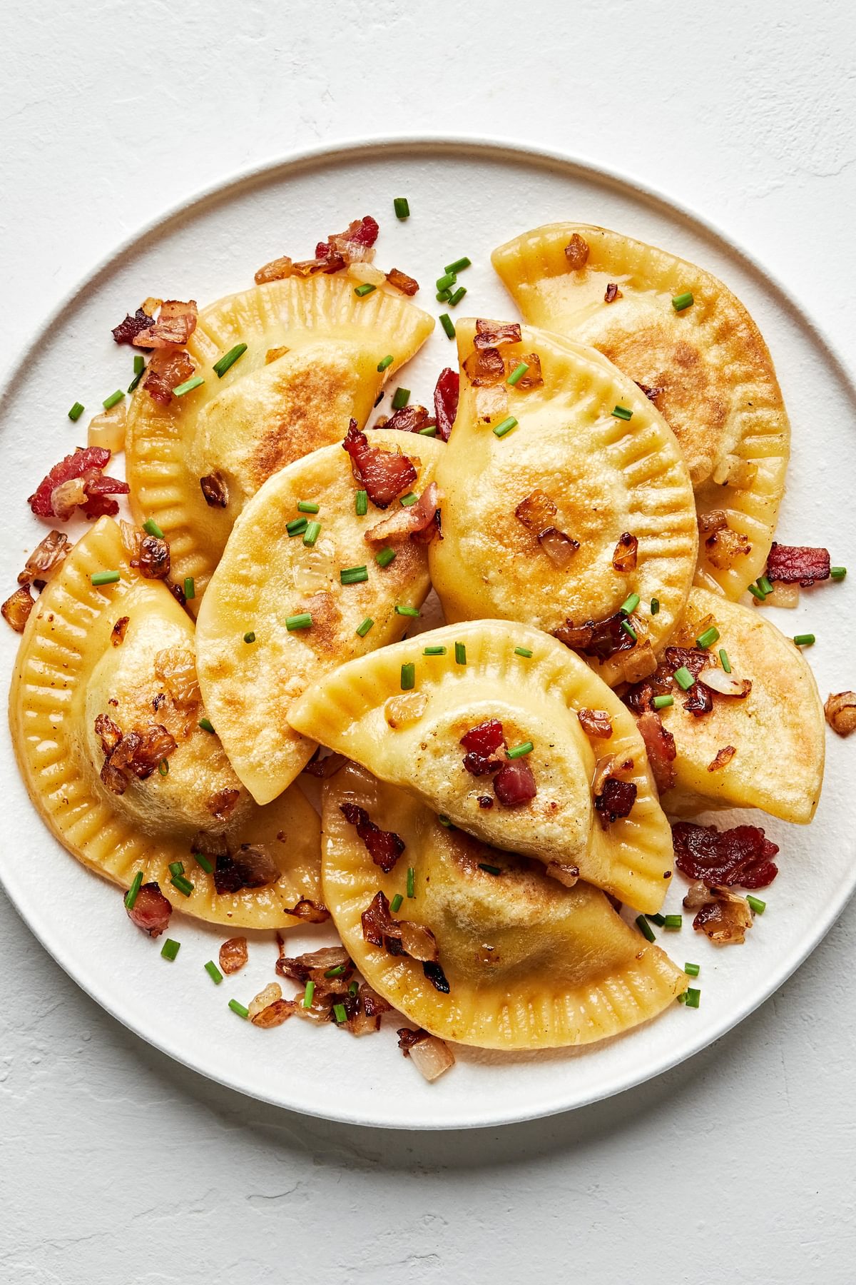 a plate of homemade pierogis: potato filled dumplings boiled then fried in a skillet with onion and bacon