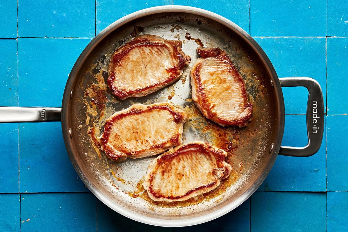 4 (1/2-inch) pork chops being browned in olive oil in a skillet