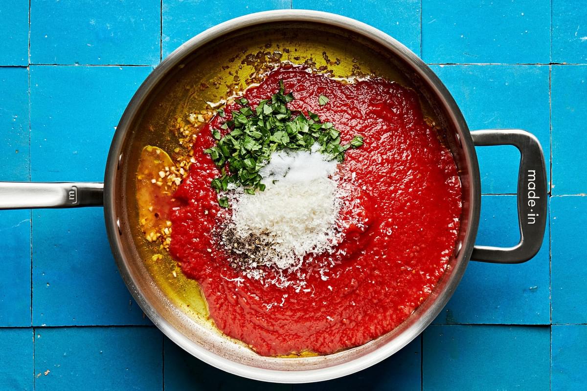 olive oil, garlic, tomatoes, pepper, basil, parmesan, sugar, and vinegar cooking in a skillet