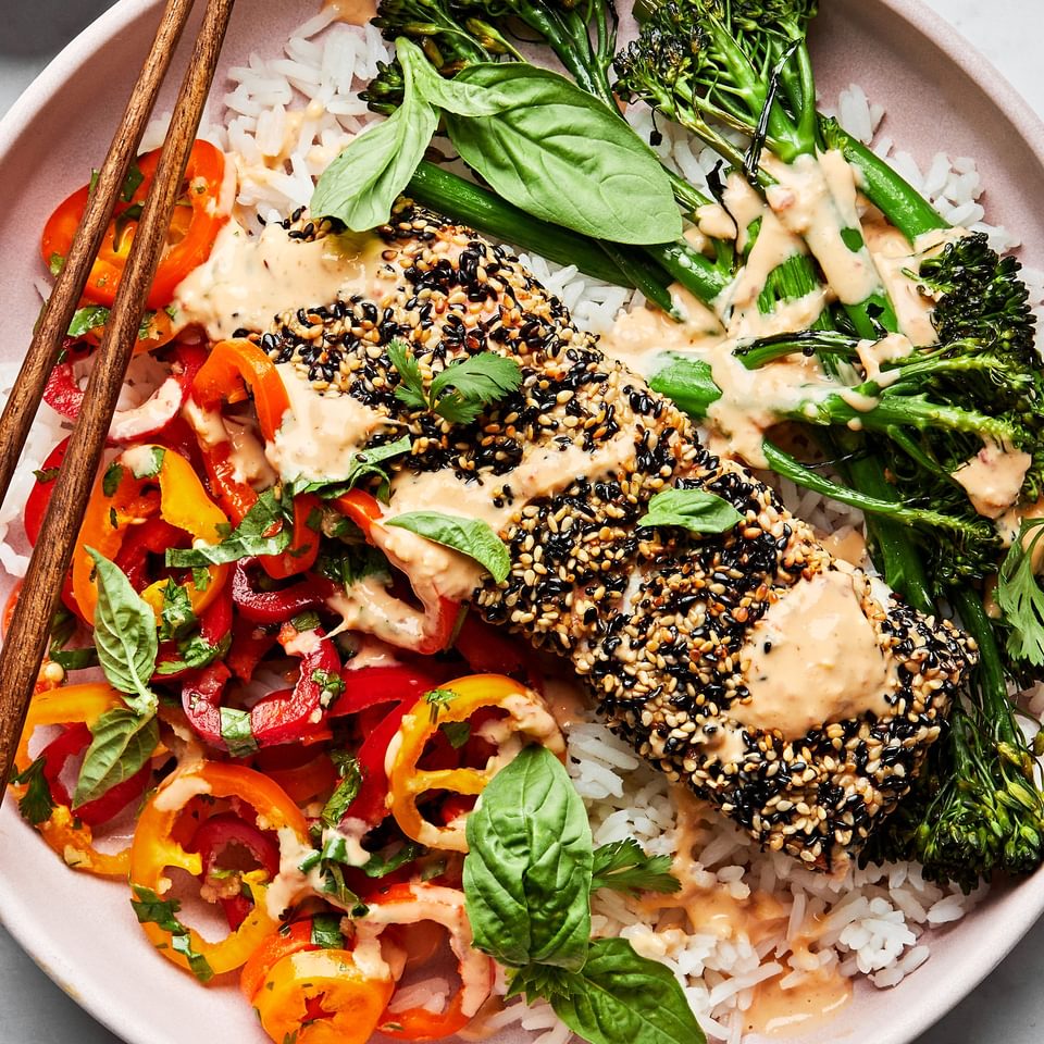Sesame crusted salmon and broccolini on top of rice served with pepper salad and drizzled with chili tahini sauce.