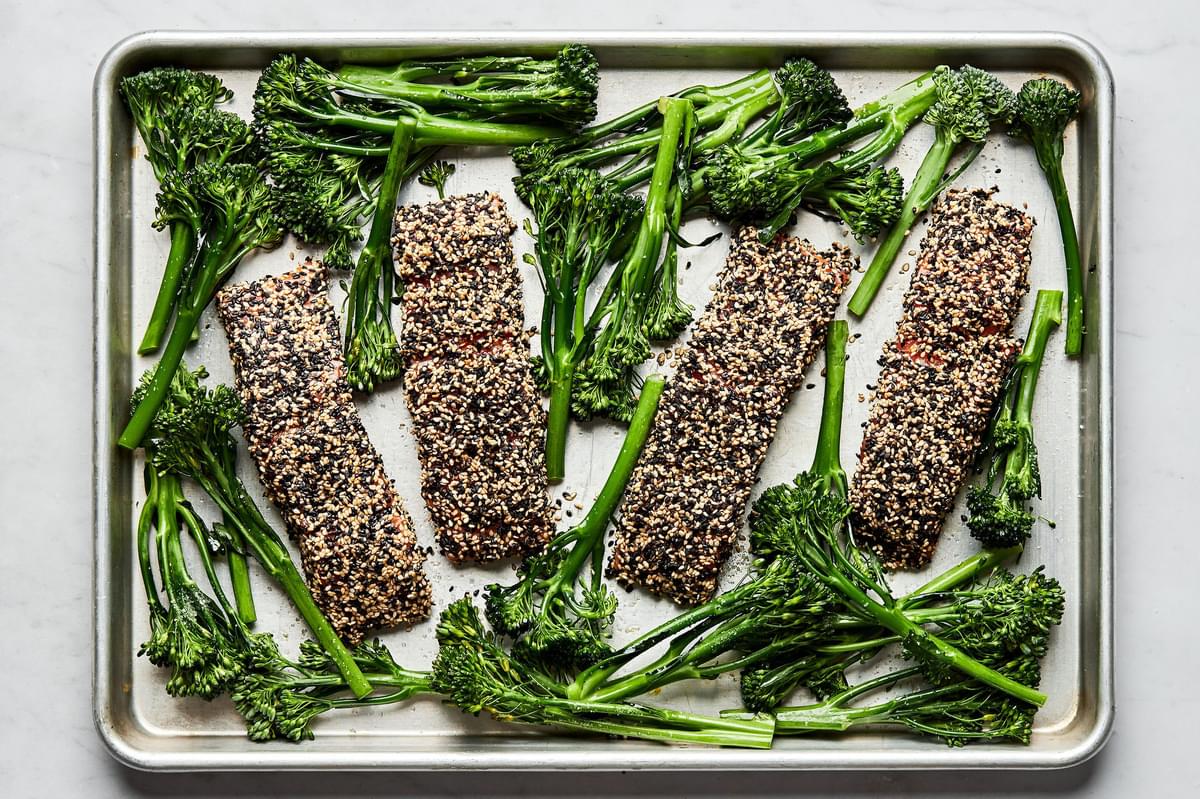 sesame crusted salmon and broccolini tossed with olive oil and salt on a baking sheet