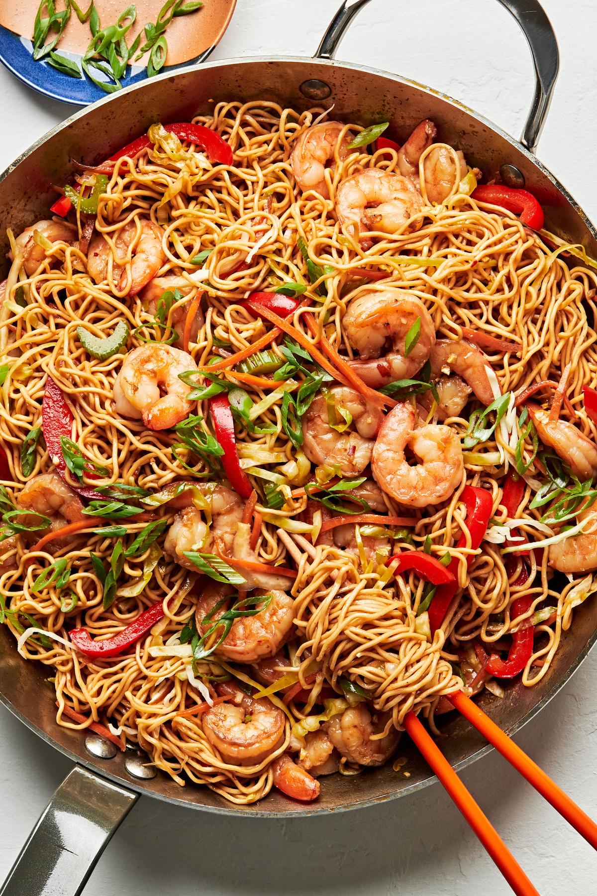 shrimp chow mein made with soy sauce, chili sauce, ginger, garlic, sesame oil & vegetables in a skillet with chopsticks