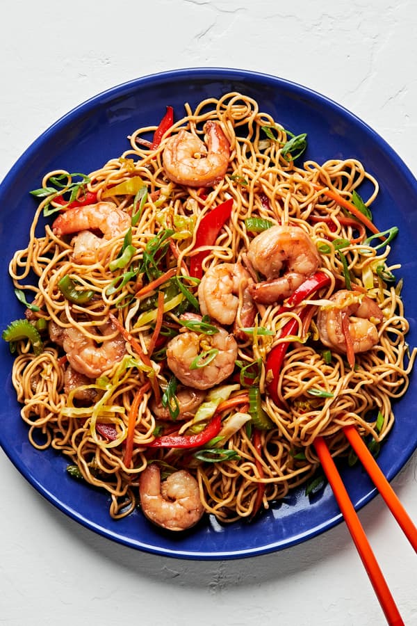 shrimp chow mein made with tamari, chili sauce, ginger, garlic, sesame oil and shredded vegetables on a plate with chopsticks