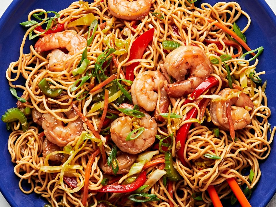 shrimp chow mein made with tamari, chili sauce, ginger, garlic, sesame oil and shredded vegetables on a plate with chopsticks