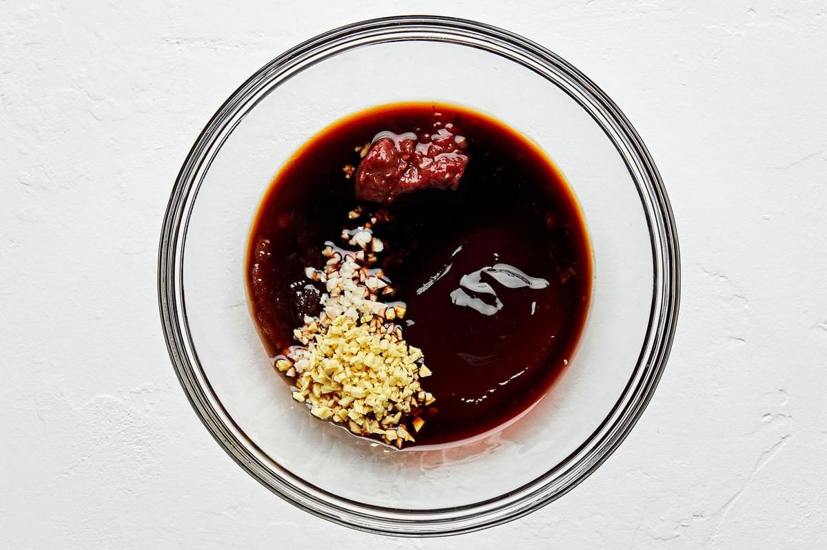 oyster sauce, soy sauce, Shaoxing, brown sugar, chili sauce, garlic, and ginger combined in a glass bowl