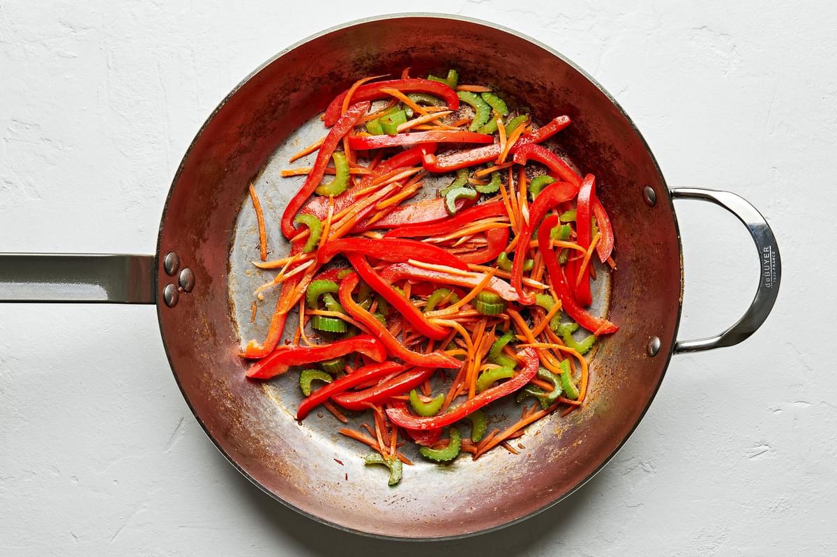 carrots, bell peppers and celery being cooked in a skillet
