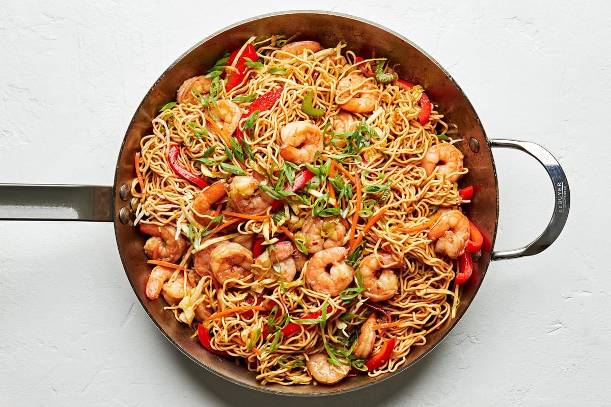 shrimp chow mein made with soy sauce, chili sauce, ginger, garlic, sesame oil and shredded vegetables in a skillet