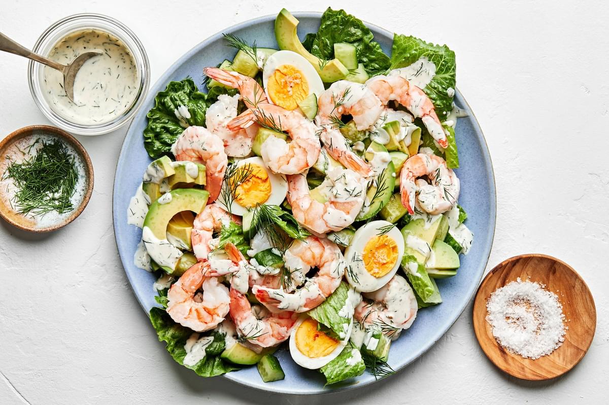 shrimp and avocado salad topped with hard boiled eggs, homemade dill dressing and flaky salt
