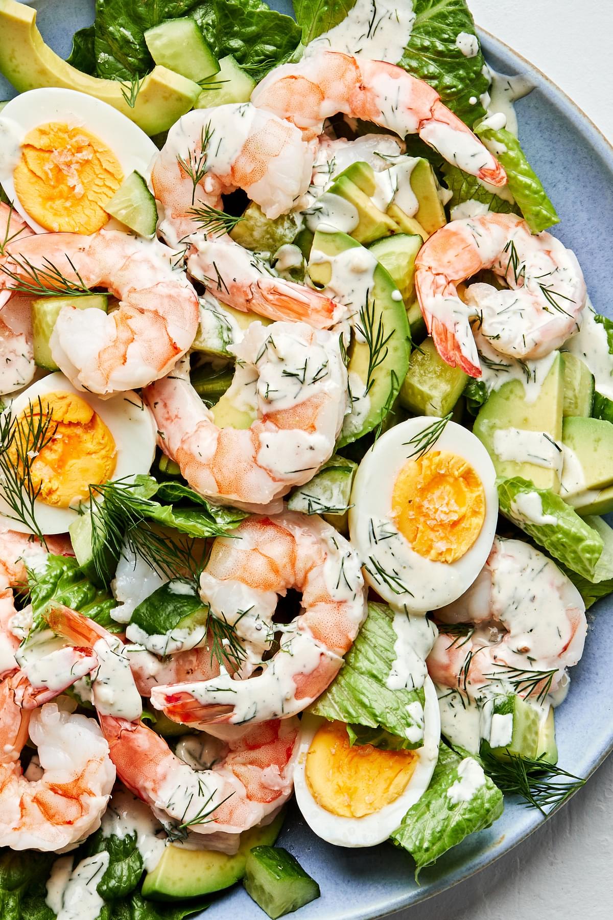 shrimp and avocado salad topped with boiled eggs, homemade dill dressing and flaky salt