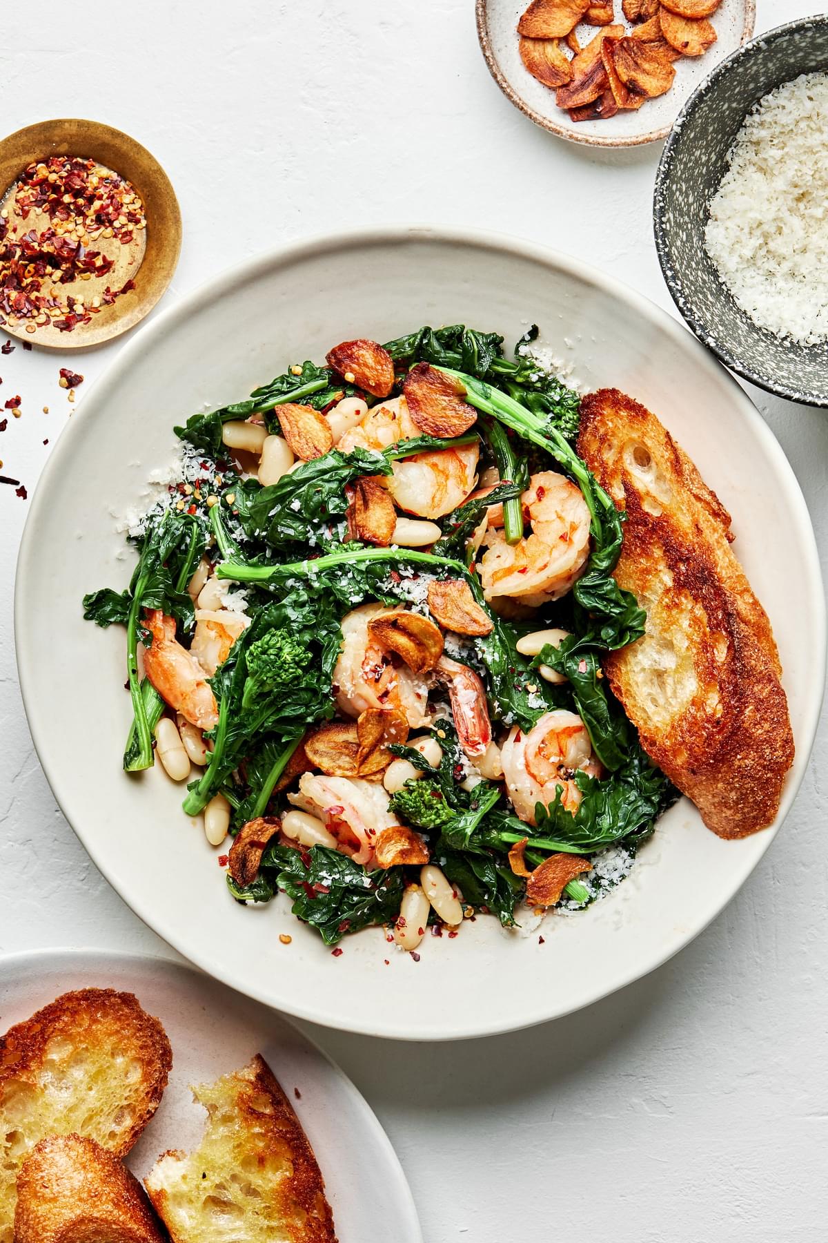 spicy broccoli rabe with white beans and shrimp in a bowl served with crusty bread
