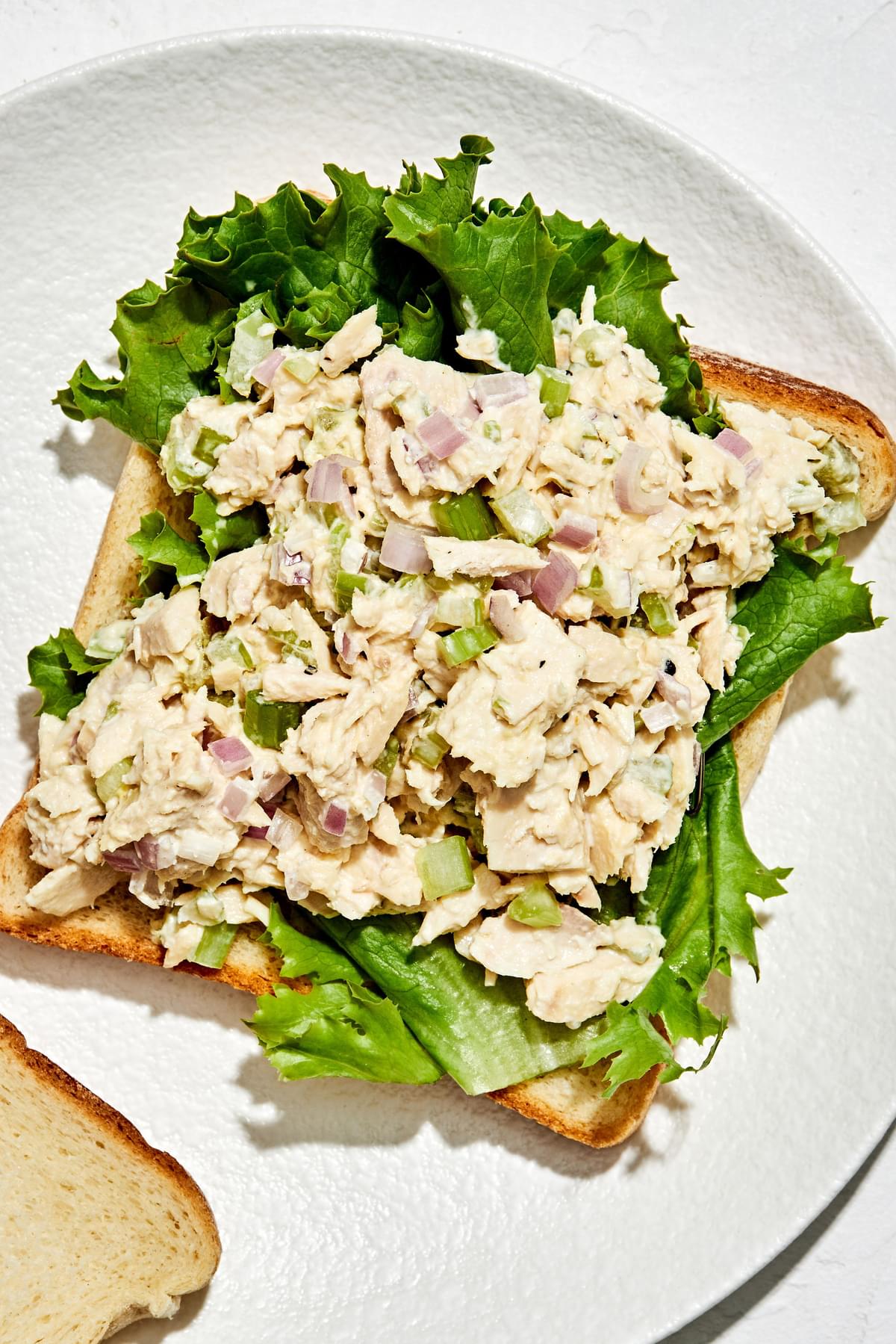 bread on a plate topped with lettuce and homemade tuna salad