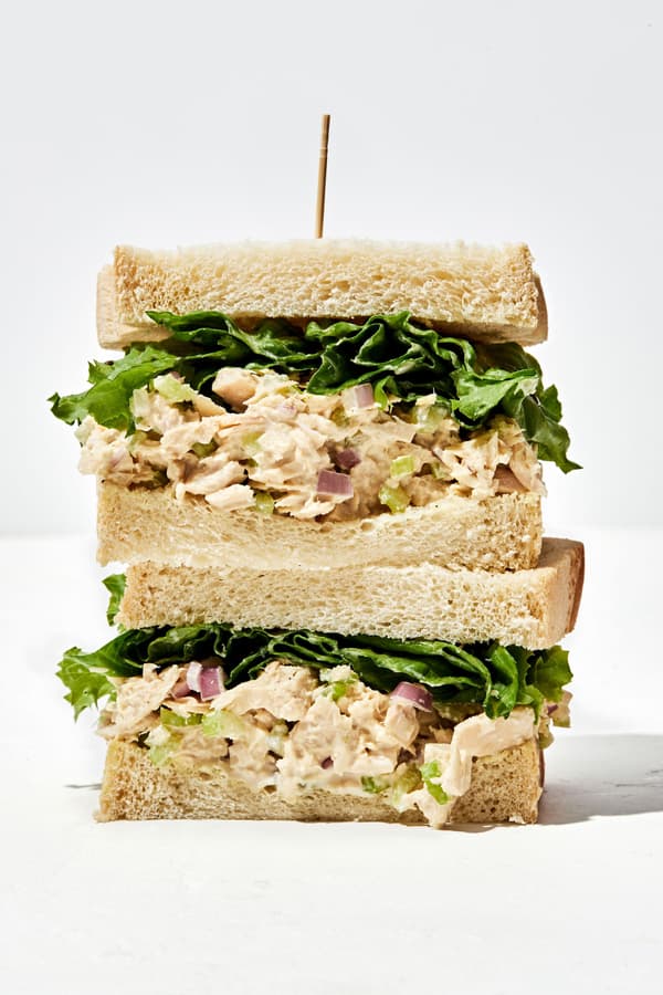 a tuna salad sandwich cut in half and stacked on top of each other with a toothpick sticking out of the top