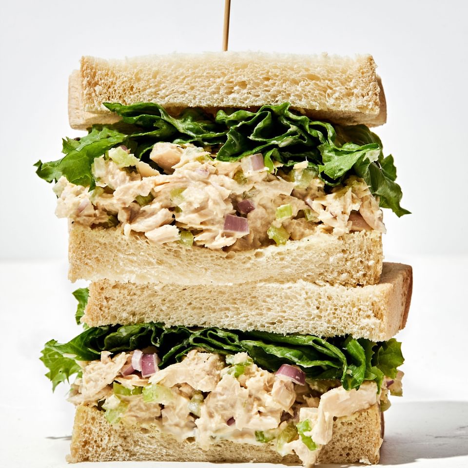 a tuna salad sandwich cut in half and stacked on top of each other with a toothpick sticking out of the top