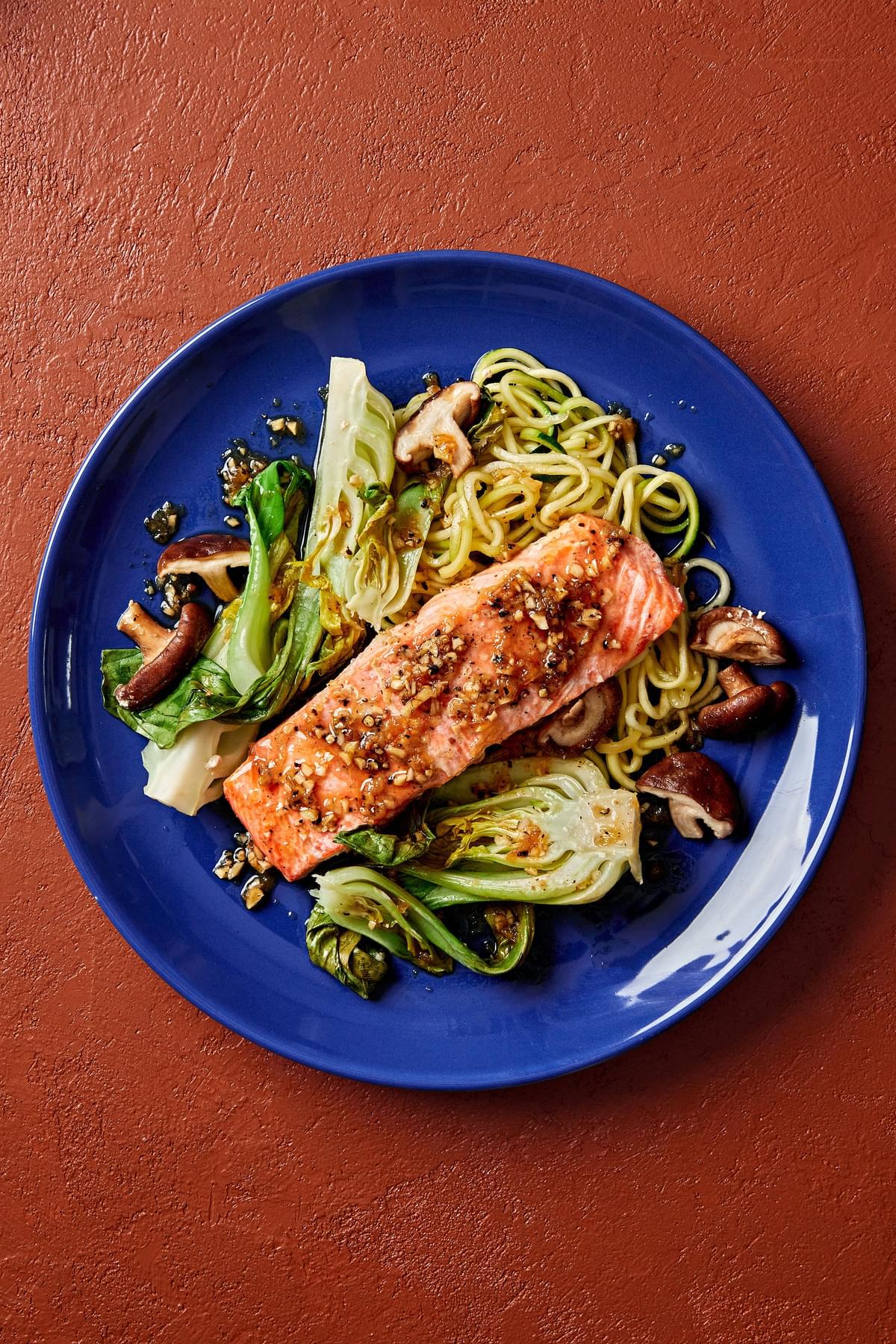 garlic ginger salmon on a plate with zucchini noodles, bok choy and shitake mushrooms