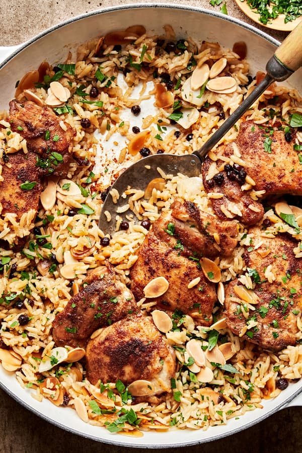 Almond and Currant Pilaf with Chicken in a skillet with a serving spoon
