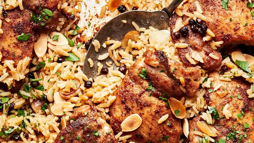 Almond and Currant Pilaf with Chicken in a skillet with a serving spoon
