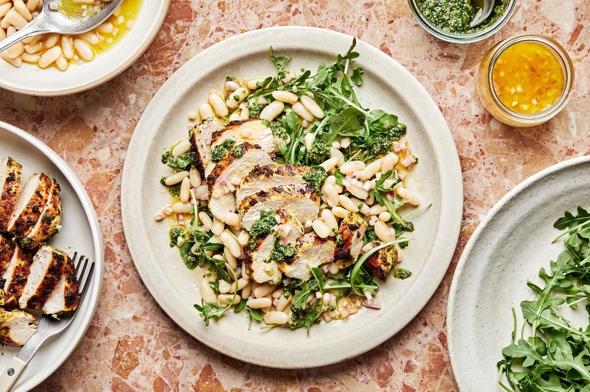 arugula and white bean salad with homemade dressing topped with pesto chicken