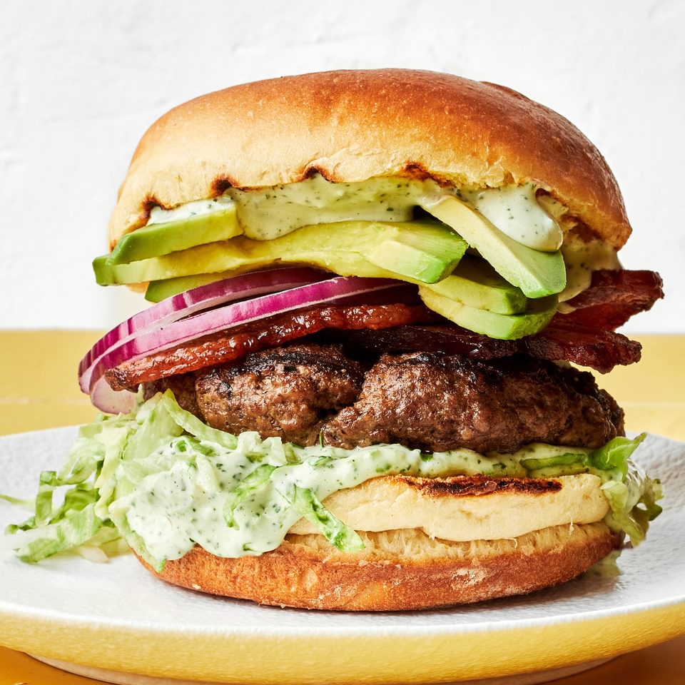 a homemade avocado burger with bacon, lettuce, red onion and jalapeño aioli