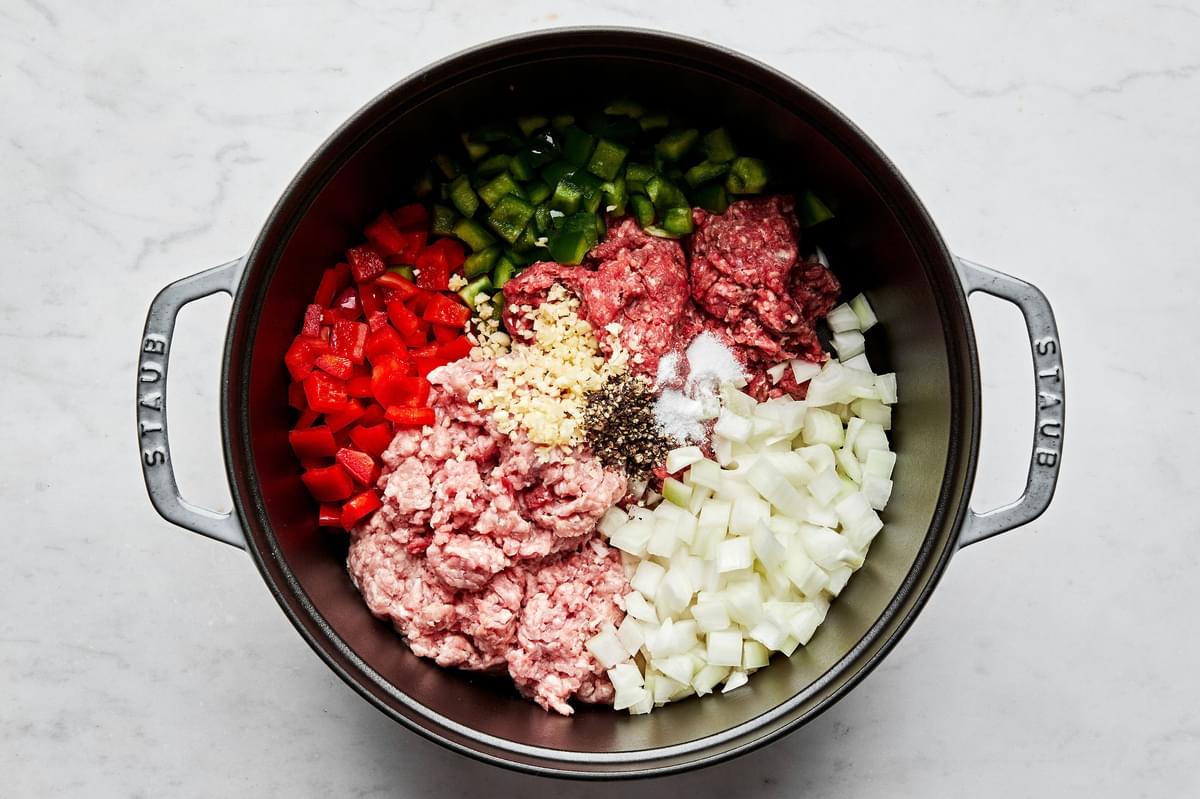 ground beef, ground pork, diced onion, bell peppers, garlic, salt, and black pepper being cooked in a large soup pot