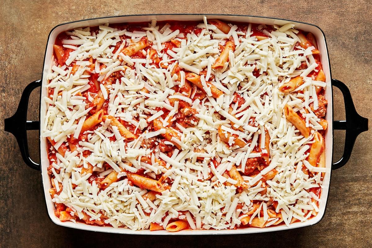 Cooked Mostaccioli and pasta sauce spread into a 9x13 baking pan topped with mozzarella cheese