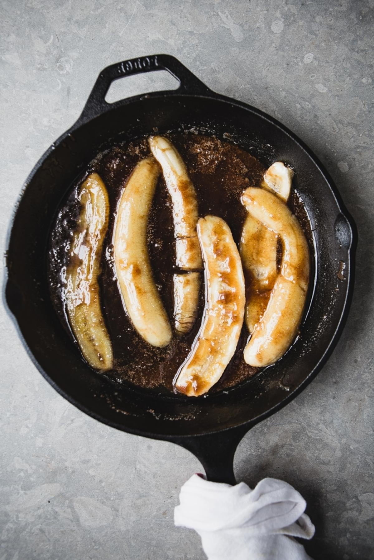 Bananas caramelizing in brown sugar in a cast iron skillet