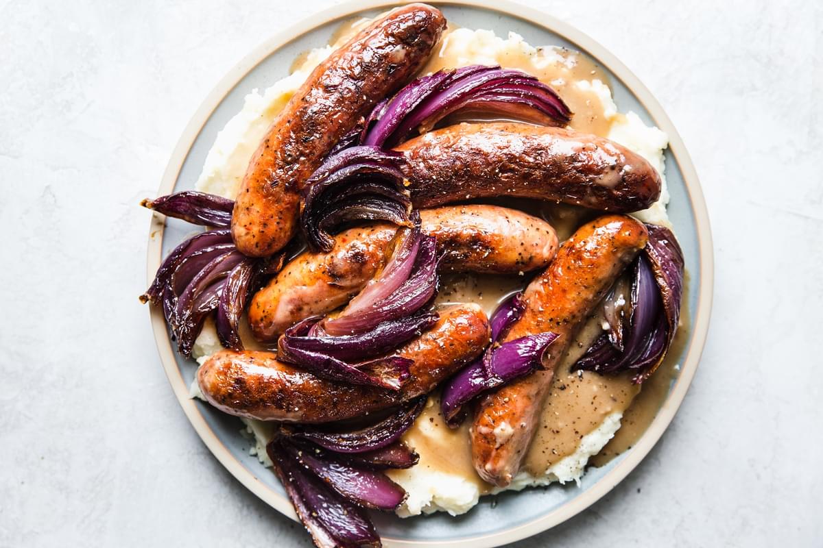 a plate of bangers and mash with caramelized onion with homemade gravy