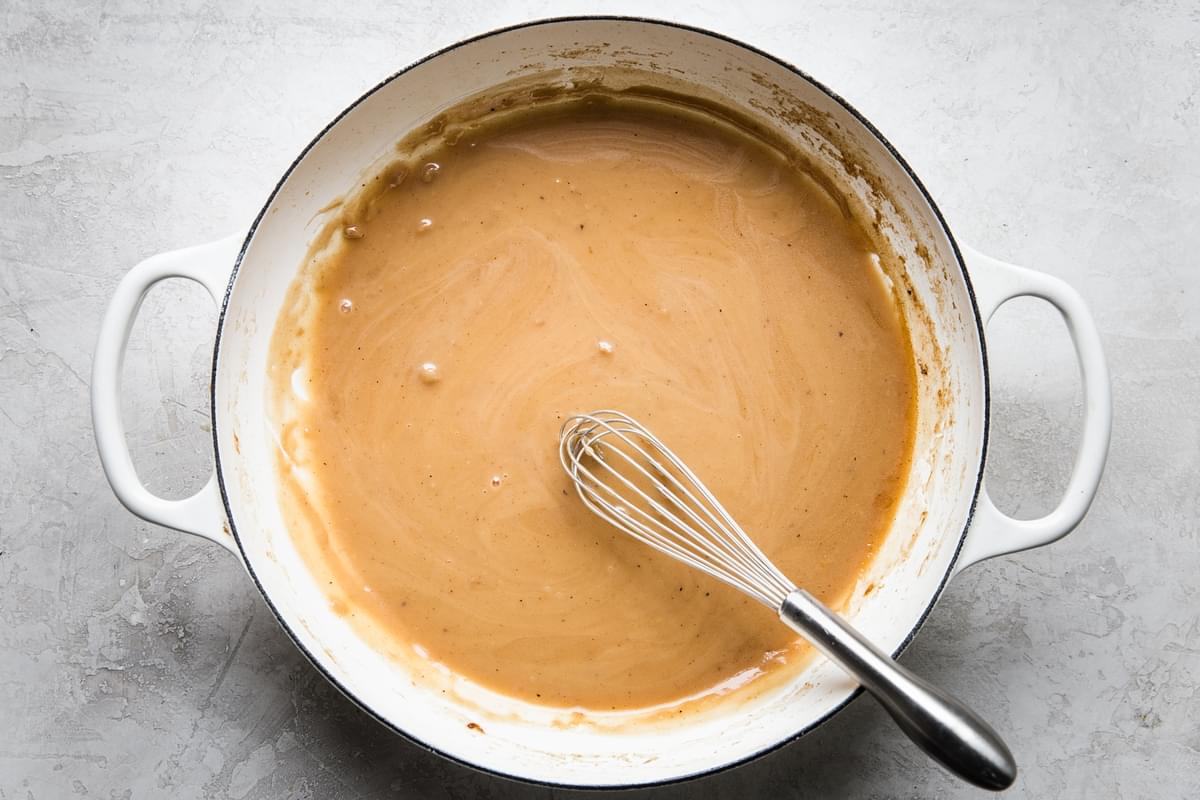 homemade gravy being whisked in a skillet made with flour, butter, salt and pepper