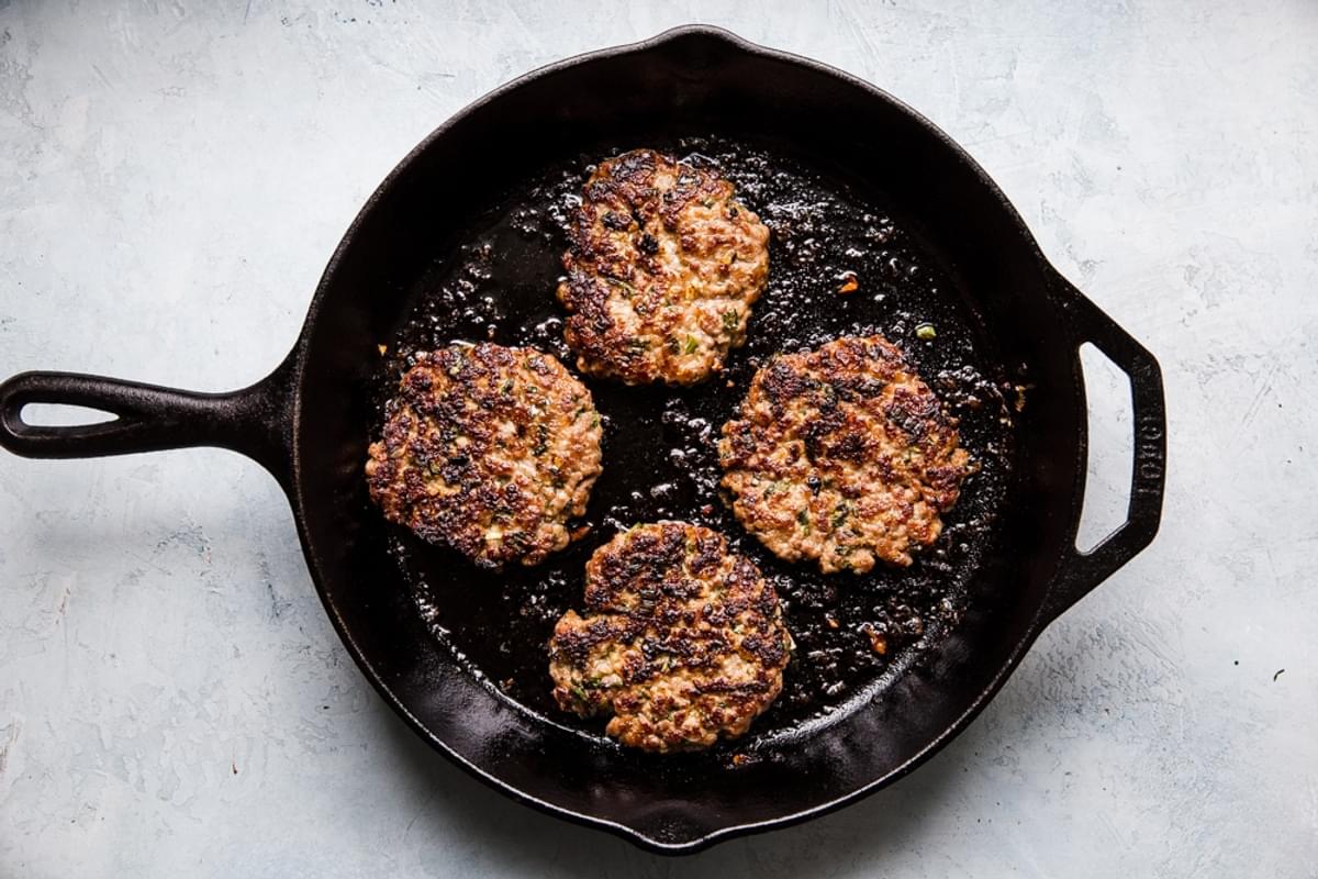 banh mi burger pork patties in a cast iron pan