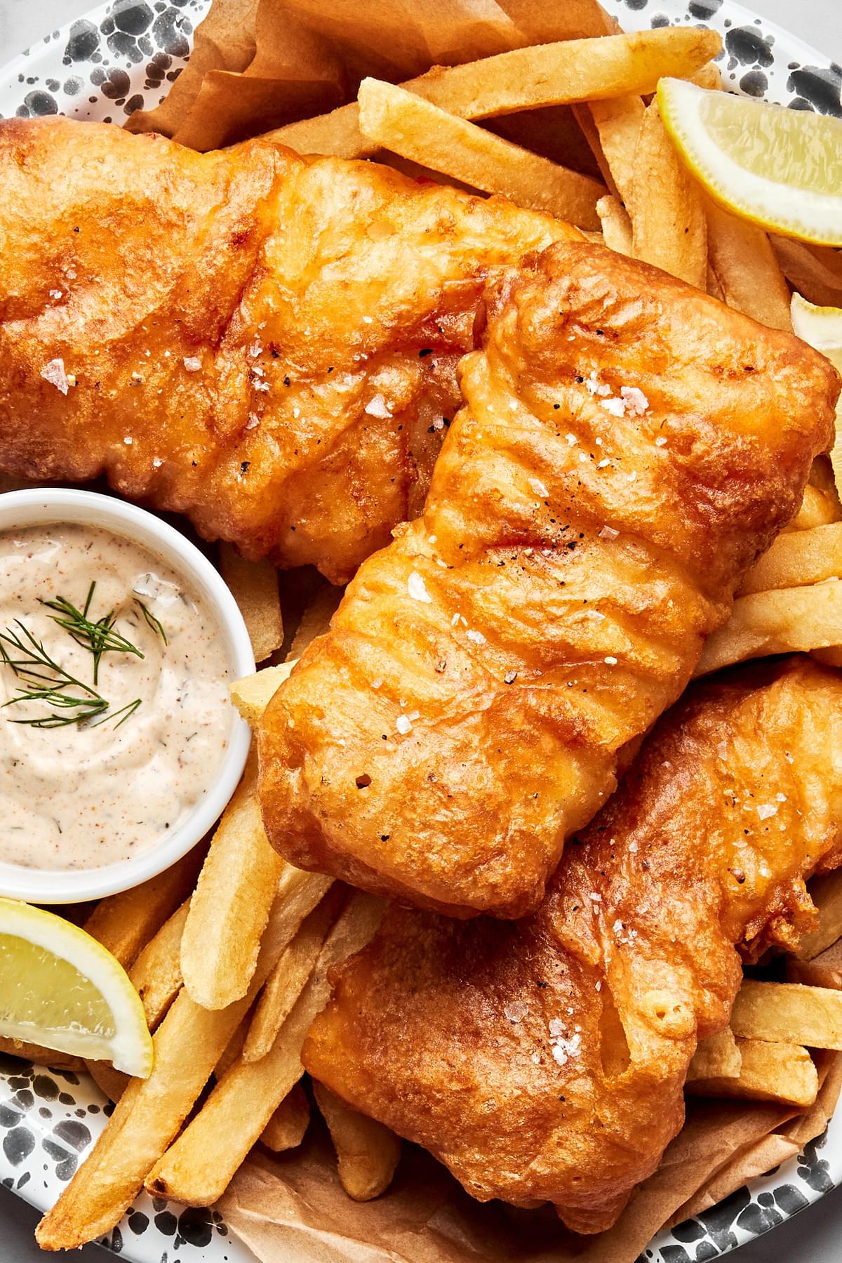 homemade beer battered fish served with french fries, lemon wedges and tartar sauce