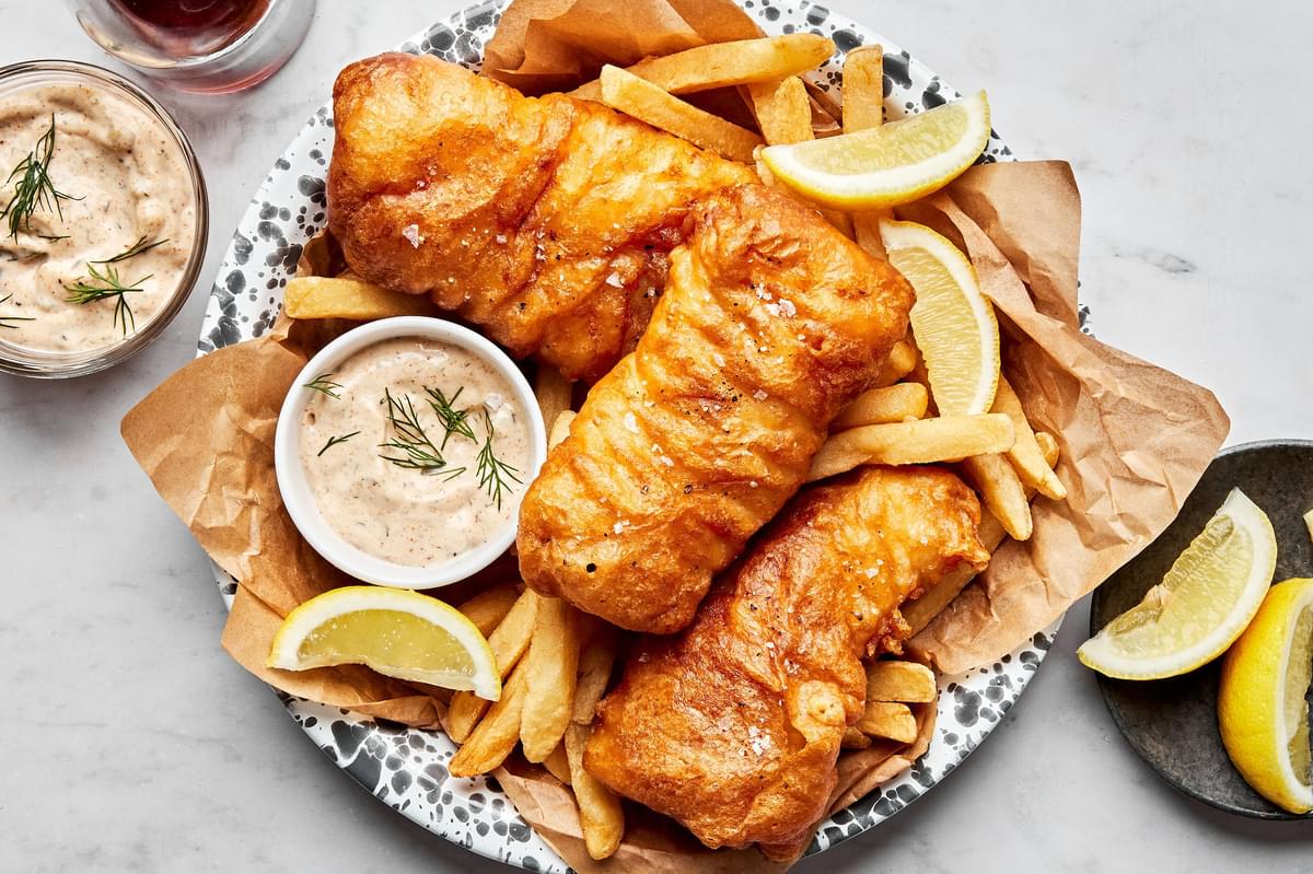 homemade beer battered fish served with french fries, lemon wedges and tartar sauce