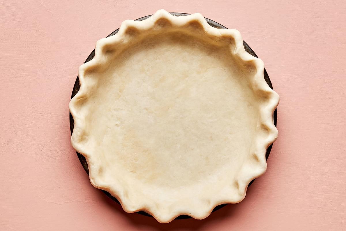 a raw butter pie crust pressed into a pie plate with the edges crimped