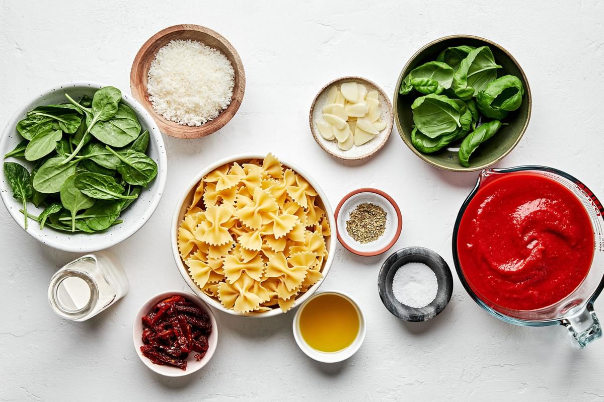 pasta, basil, canned tomatoes, spinach, sun-dried tomatoes, spices, cream and Parmesan in prep bowls