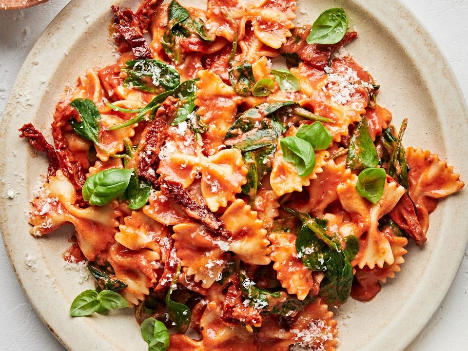 bow tie pasta made with tomatoes, basil, cream, spinach, sun dried tomatoes and topped with parmesan