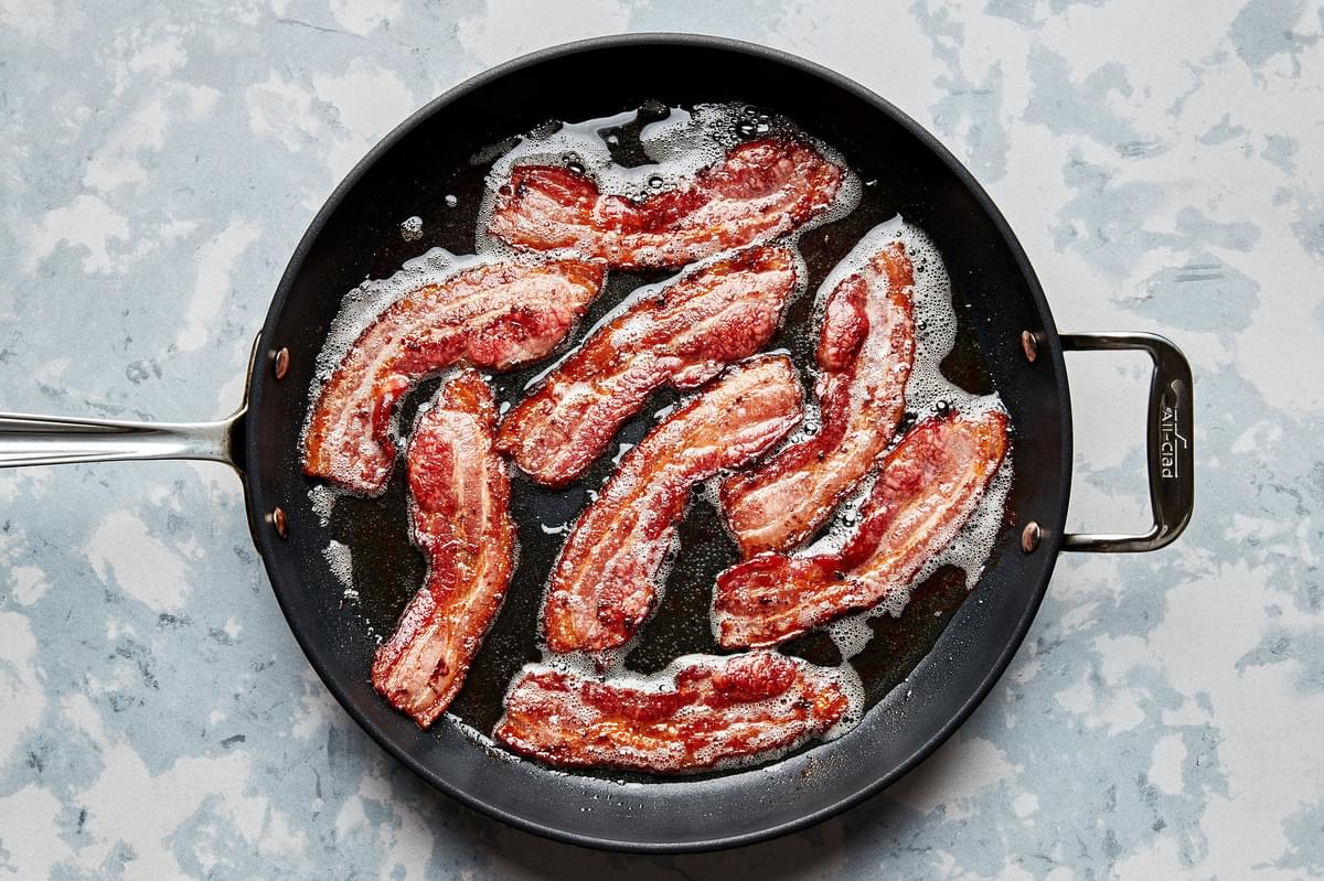 bacon being fried in a skillet