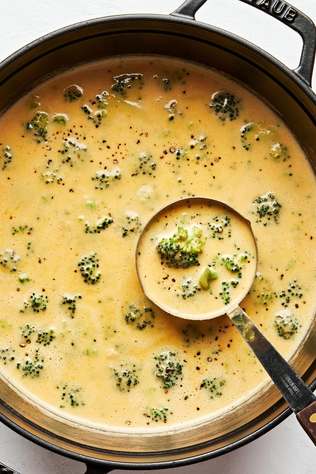 a pot of homemade broccoli cheddar soup being scooped with a ladle