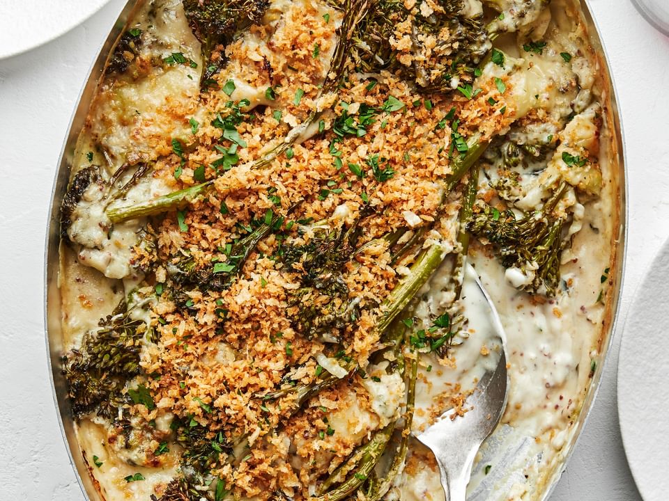 homemade broccolini au gratin being scooped out of a baking dish