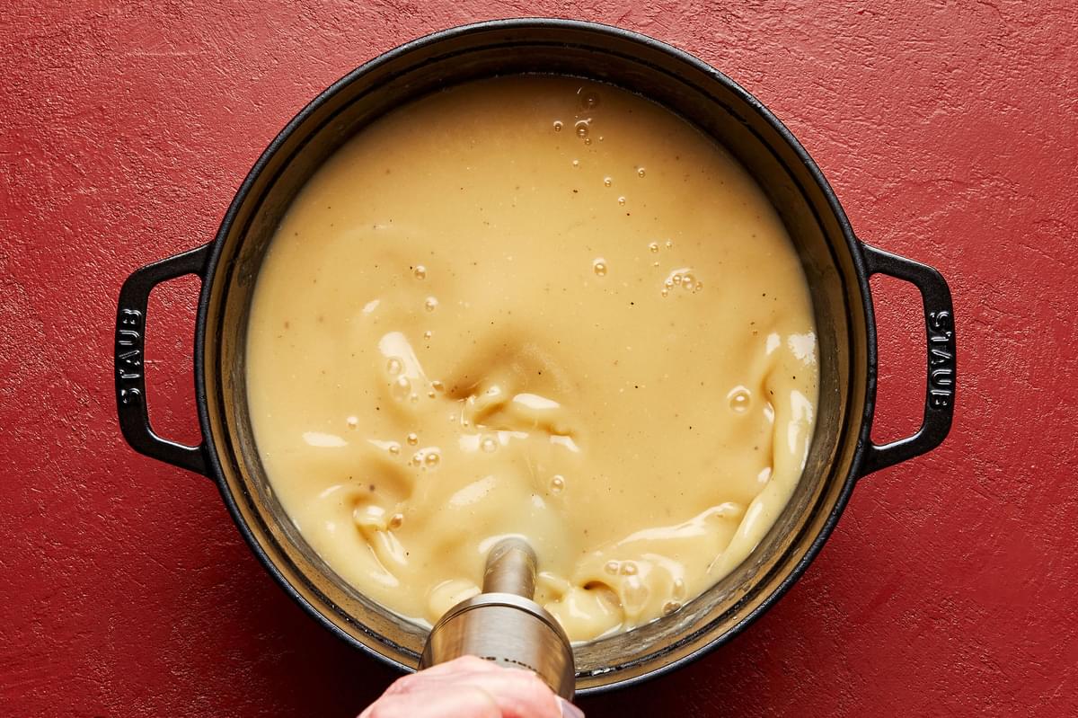 soup being blended with an immersion blender in a large soup pot