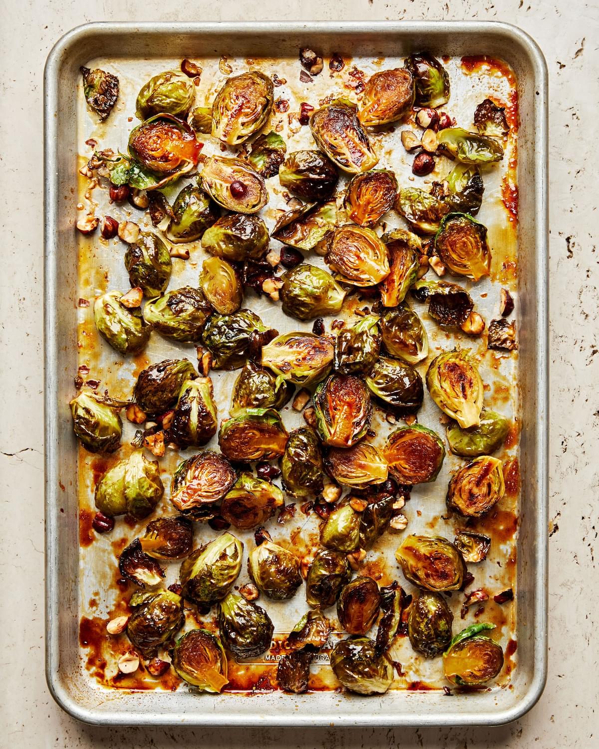 roasted brussels sprouts tossed with olive oil, brown sugar, maple syrup, lemon juice, salt, and cayenne on a baking sheet