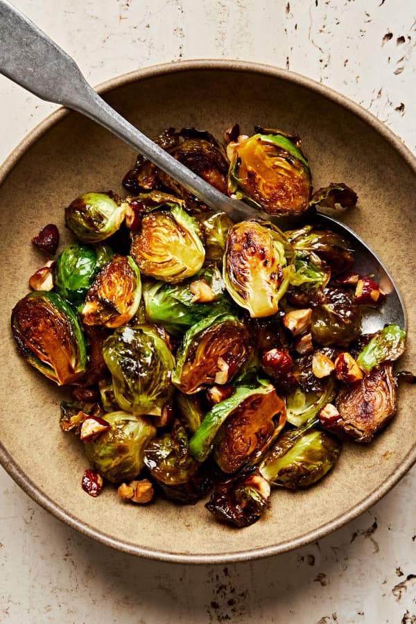 candied brussels sprouts with hazelnuts in a serving bowl with a spoon