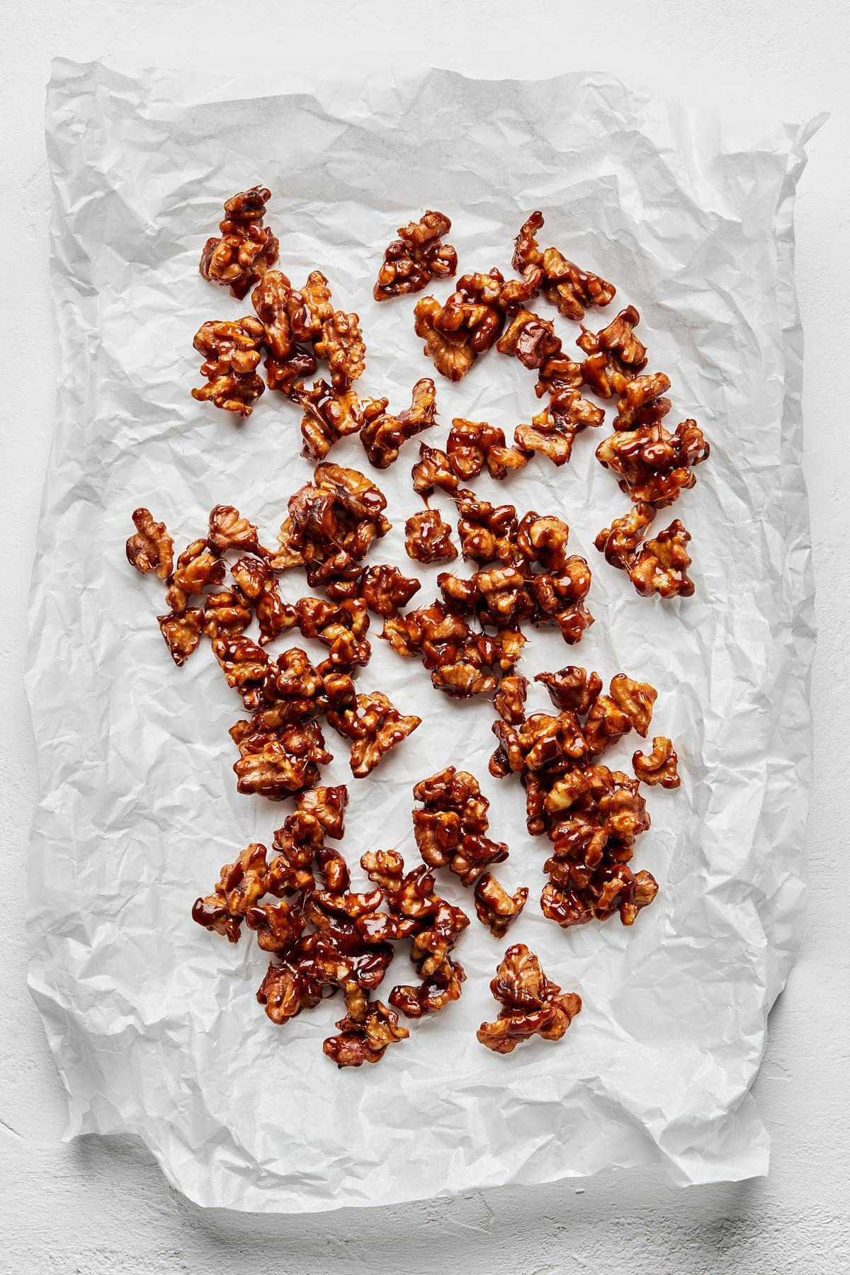 homemade candied walnuts cooling on parchment paper