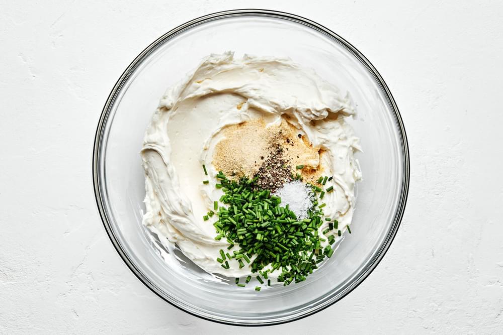 cream cheese, sour cream, onion powder, garlic powder, salt, pepper and chives being combined in a bowl