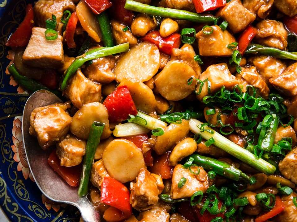 homemade cashew chicken recipe with bell pepper, garlic, ginger, green onions and soy sauce in a bowl with a spoon