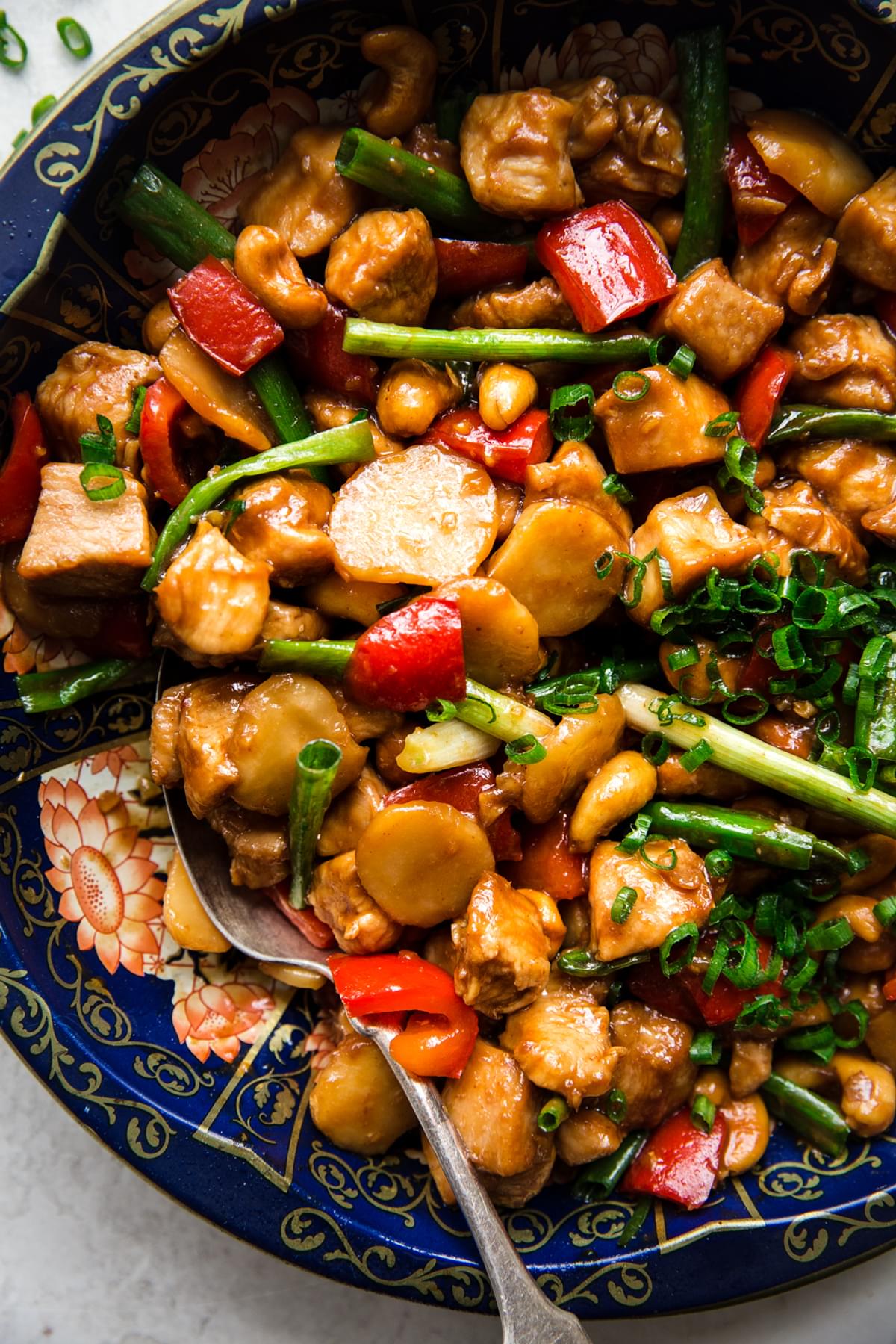 the best cashew chicken served in a bowl with green onions, water chestnuts, and bell peppers, with ginger and garlic