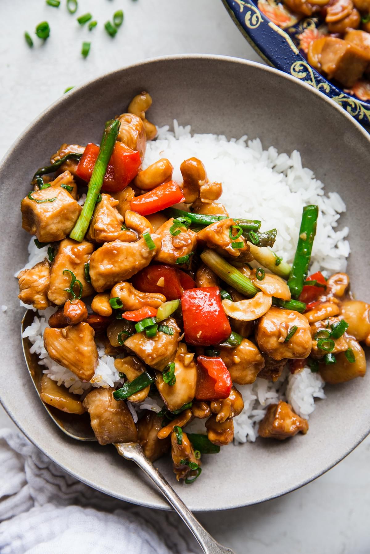 homemade cashew chicken recipe with bell pepper, garlic, ginger, green onions and soy sauce in a bowl with rice